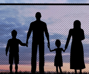 stock image of silhouette of a family standing in front of a fence